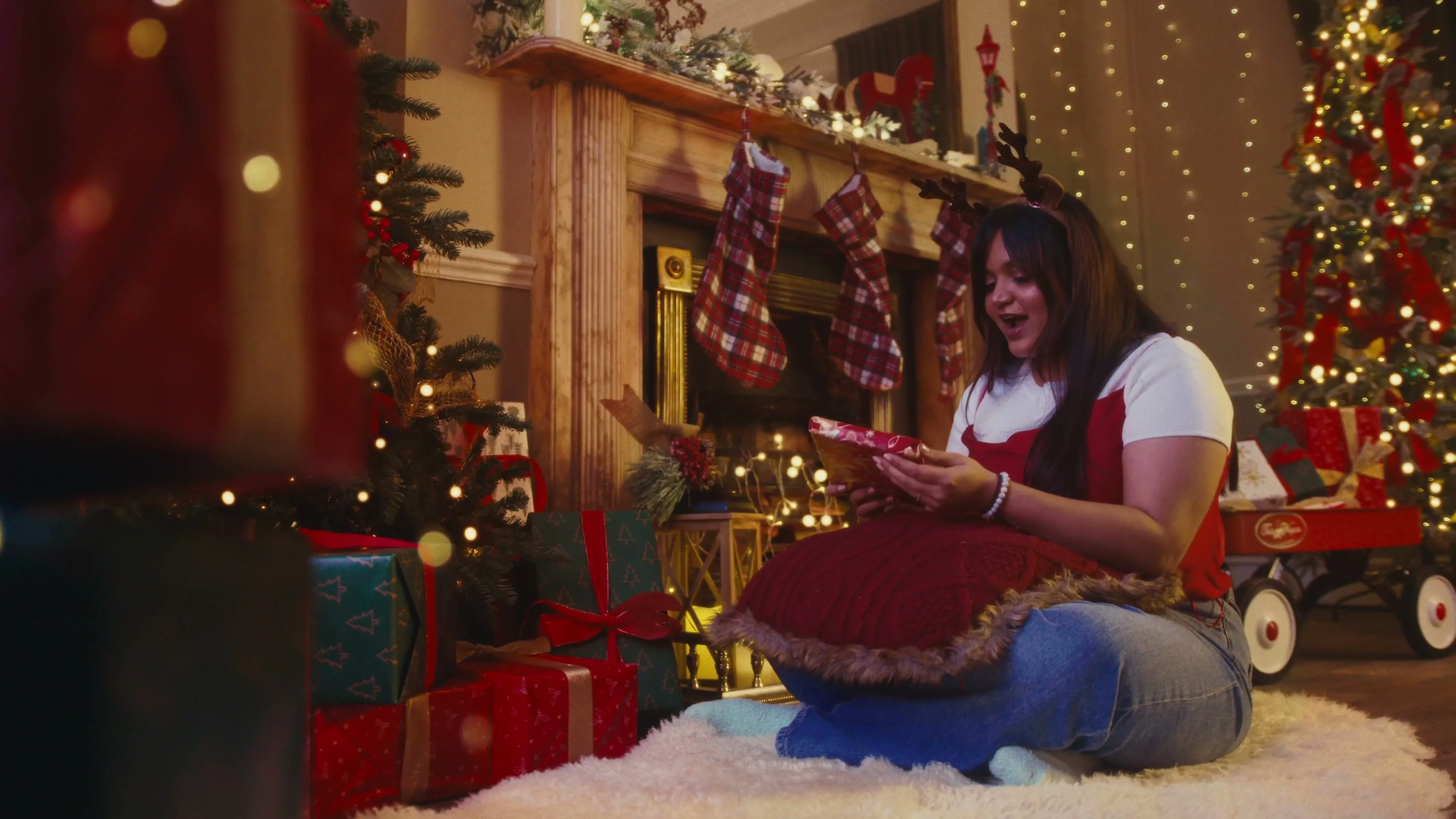 A woman opens a Christmas present by the fire, from the Paperblanks Christmas advert