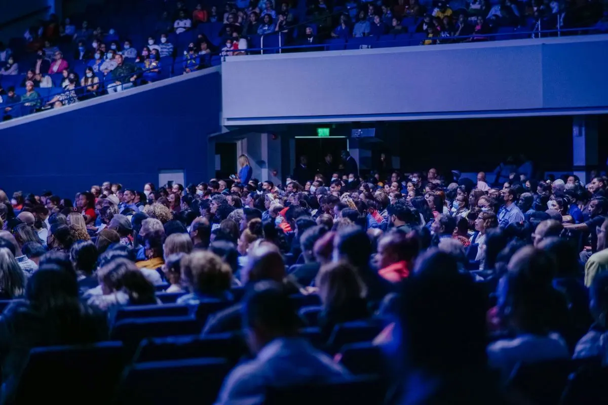 Illustrative photo: packed conference auditorium in blue light