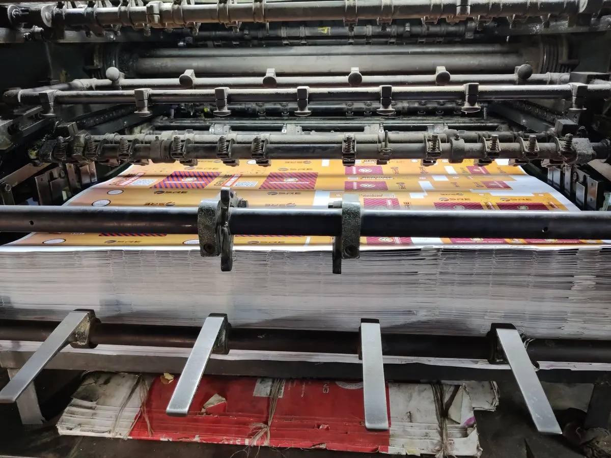 Illustrative photo: industrial printing press feeding printed sheets
