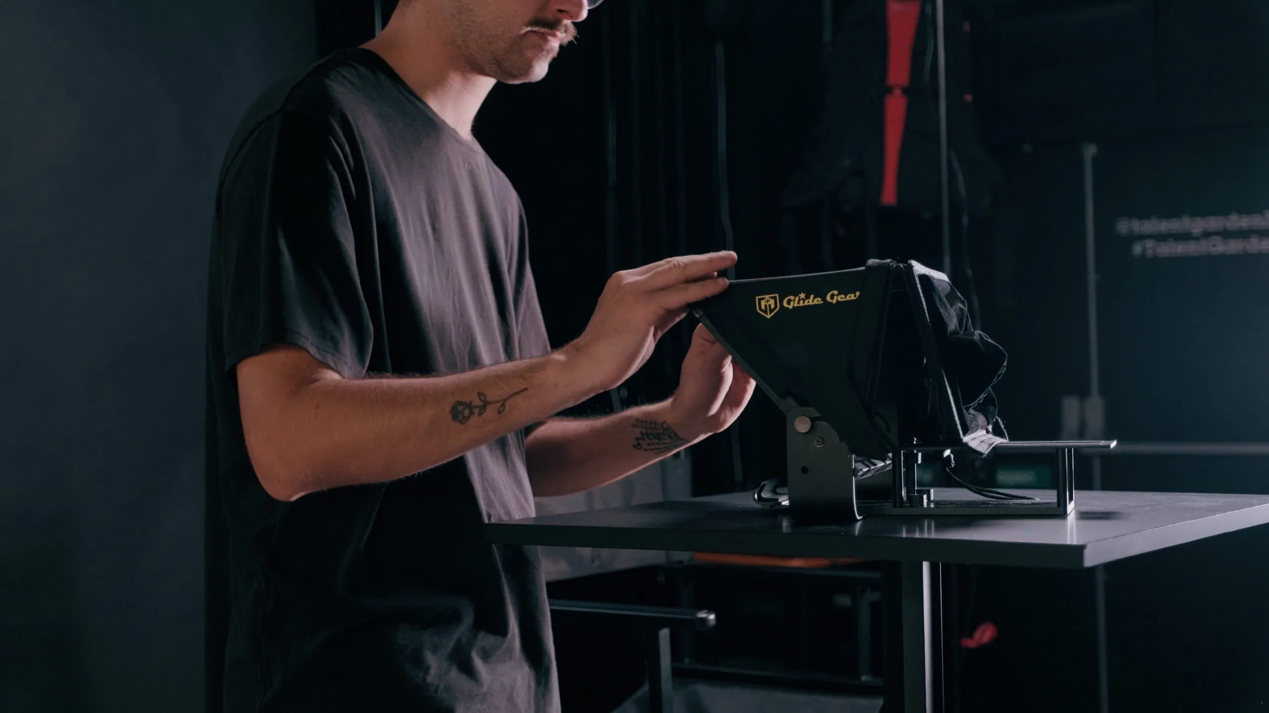 A crew member setting up a teleprompter in a dark studio
